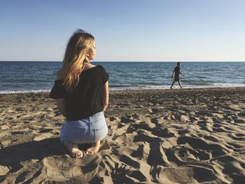 Woman walking on beach against clear sky