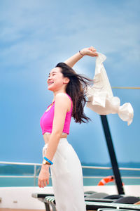 Young woman standing against sky