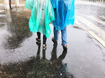 Low section of people walking on wet road
