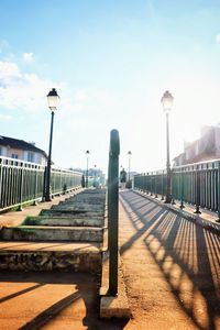 Street leading towards city against sky