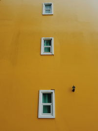 Low angle view of windows on yellow wall