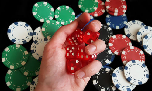 Cropped hand holding dice on gambling chips