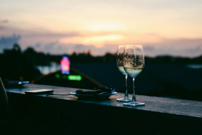 Glass of wine on table against sky during sunset
