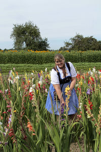 Young woman with flowers on field against clear sky