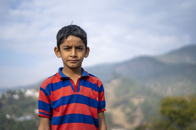 Portrait of boy standing against sky