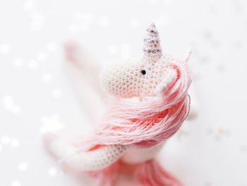 Cute fairy unicorn with pink mane. crocheted hand made toy on white background with silver stars.