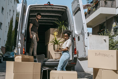 Side view of woman unloading plant from van trunk