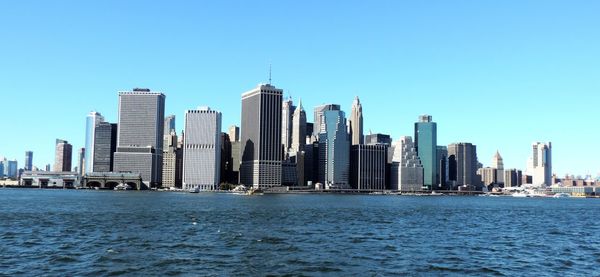 Skyscrapers in sea against clear sky