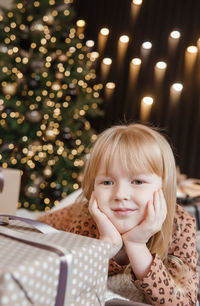 Portrait of cute girl sitting on christmas tree