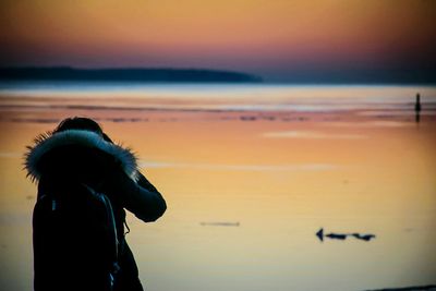 Close-up of silhouette boy on beach against sky during sunset