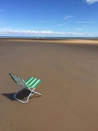 Deck chair at beach against sky