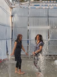 Full length of a smiling young woman splashing water