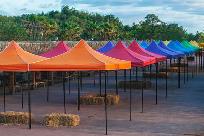 Scenic view of multi colored umbrellas by trees against sky