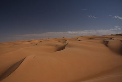 Sand dunes in desert against sky