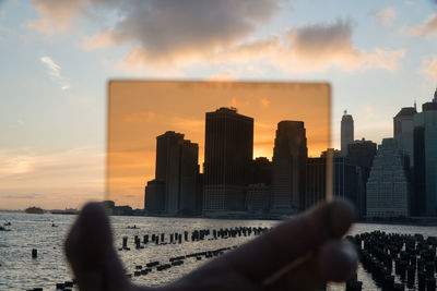 Man and buildings against sky during sunset