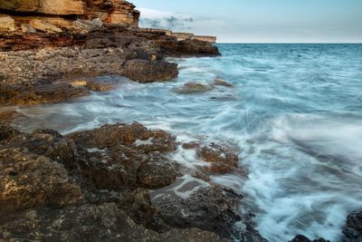 Scenic view of rocks in sea against sky