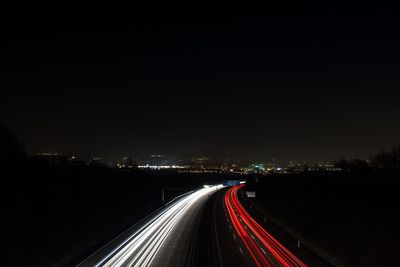 Light trails on road in city against sky at night