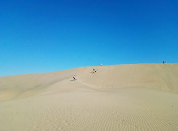 Scenic view of desert against clear blue sky