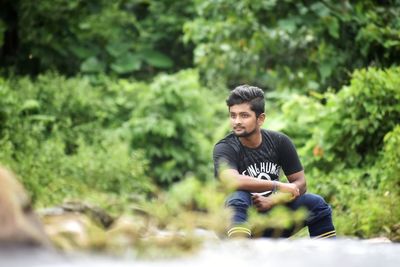 Portrait of young man sitting against plants