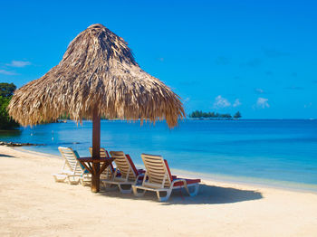 Palapa on beach against blue sky