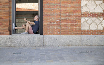 Full length of man sitting on wall