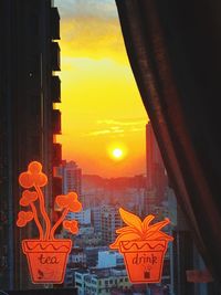 Close-up of illuminated orange cityscape against sky during sunset