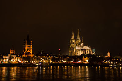 Illuminated buildings by river at night