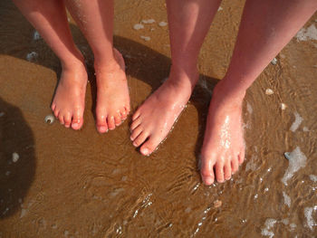 Low section of woman on wet sand at beach