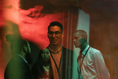 Multiracial male and female colleagues planning strategy during meeting in illuminated workshop