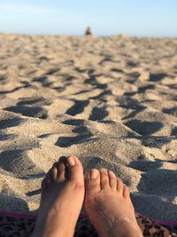 Low section of woman relaxing on sand at beach