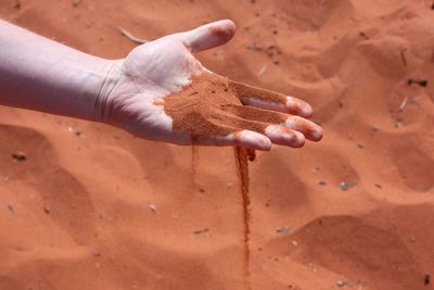 Cropped hand of man with sand at desert