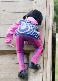 Rear view of boy climbing on wood