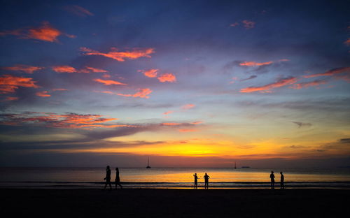 Silhouette people on beach against sky during sunset