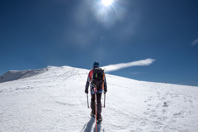 Rear view of person riding motorcycle on snowcapped mountain against sky