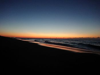 Scenic view of beach against clear sky during sunset