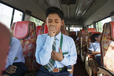 Boy coughing while sitting in bus