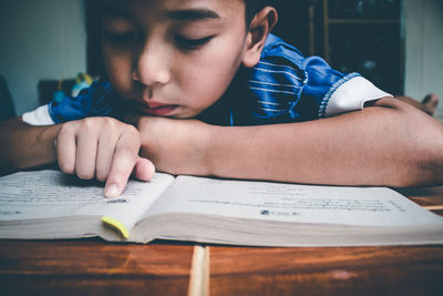 Close-up of boy with book on table