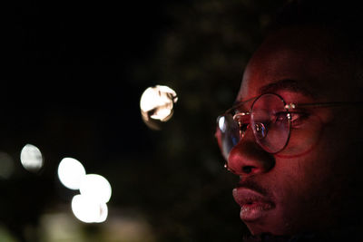 Close-up portrait of young man looking away at night