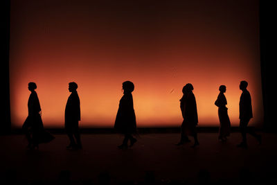Silhouette people on beach against sky during sunset