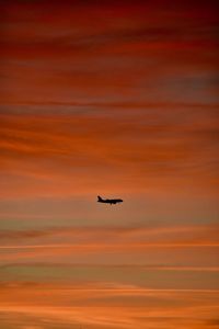 Airplane flying in sky during sunset