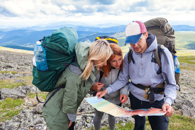 A team of travelers from two women and men with backpacks orient themselves to the terrain