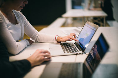 Midsection of woman using mobile phone while sitting on table