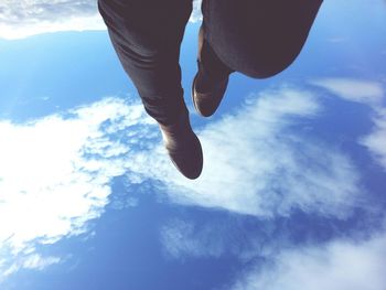 Low section of woman standing against blue sky
