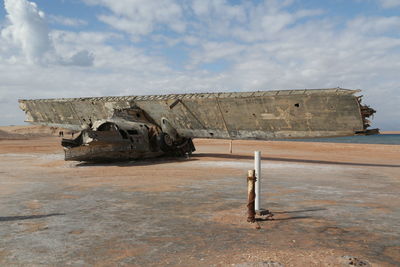 Abandoned boat on beach against sky