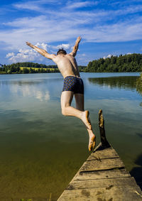 Rear view of man diving in lake against sky