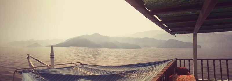 Scenic view of lake by mountains in foggy weather