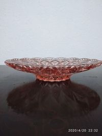 Close-up of glass container on table against wall