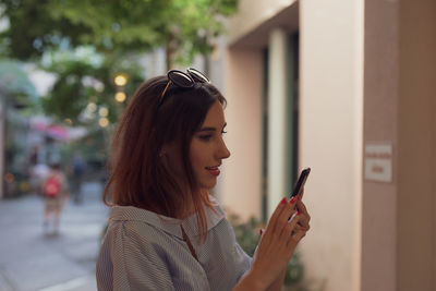 Young woman using phone while standing at city