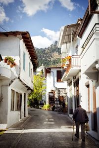Rear view of man outside house against sky