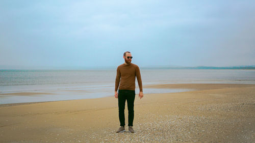 Full length of man standing on beach against sky